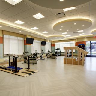 A spacious and well-lit rehabilitation center equipped with therapy tools and exercise equipment.