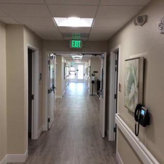 A well-lit hallway in a building with an exit sign and artwork on the walls.