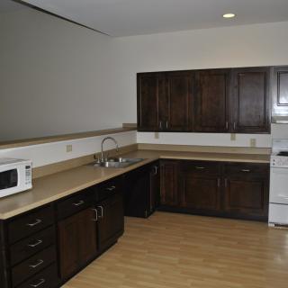 A modern kitchen with dark wood cabinets, a microwave, and an oven.