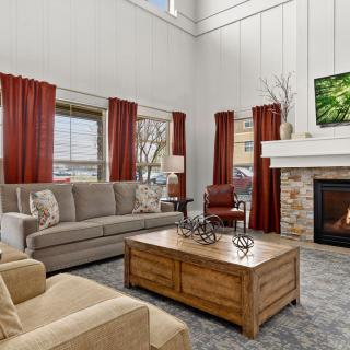 A cozy living room with a sofa, fireplace, and large windows adorned with red curtains.