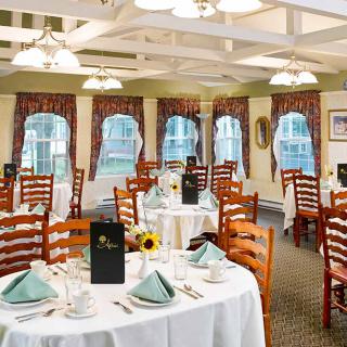 An elegant restaurant dining area with neatly arranged tables and chairs, featuring white tablecloths and decorative place settings.