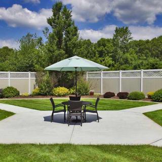 A serene backyard patio area with outdoor furniture, umbrella, and lush landscaping.