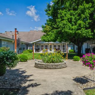 A tranquil courtyard garden with lush greenery and colorful flowers on a sunny day.