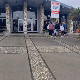 Customers entering a retail store on a cloudy day.