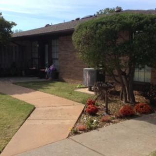 A suburban house with a landscaped yard featuring a pathway and various plants.