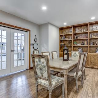 A cozy dining room featuring a wooden table, floral chairs, and a well-stocked bookshelf.