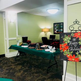 A festive holiday setup in a welcoming lobby with a decorated table and cheerful signage.