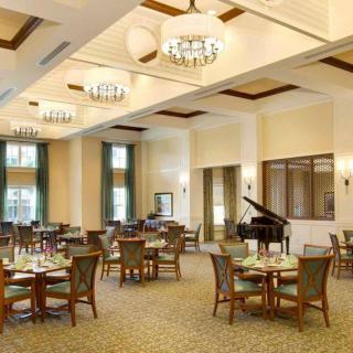 An elegant dining area featuring multiple tables and a grand piano.