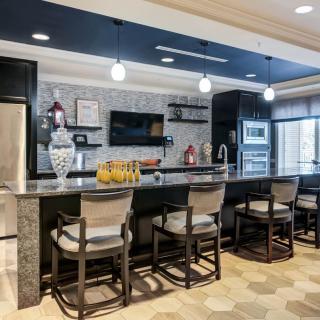 A modern kitchen with sleek countertops, bar stools, and pendant lighting.