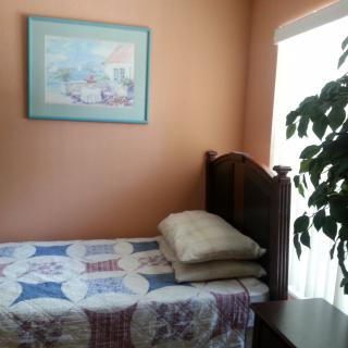 Cozy bedroom with a single bed, quilt, and decorative painting.