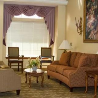 A traditional living room with plush sofas, a coffee table, and elegant drapery framing a large window.