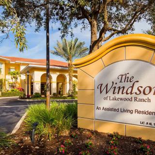 Entrance to The Windsor of Lakewood Ranch, an assisted living residence with landscaped surroundings.