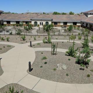 A courtyard with desert landscaping and winding pathways surrounded by buildings under a clear blue sky.