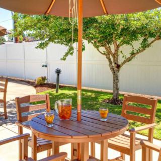 A cozy outdoor patio setup with a wooden table, chairs, and umbrella, surrounded by a lush garden.