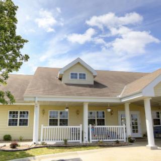 A charming residential house with a porch, set against a blue sky with scattered clouds.