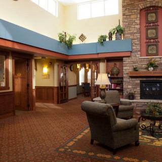 A cozy lobby area featuring comfortable armchairs, a fireplace, and warm decor.