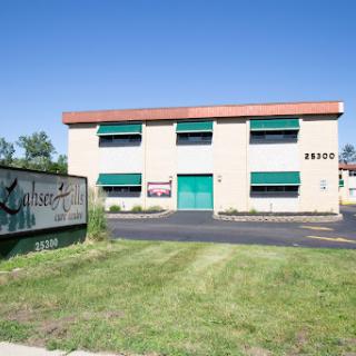 A commercial building with green awnings and a grassy area in front.