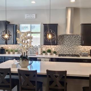 A modern kitchen with a large island, pendant lights, and a stylish backsplash.