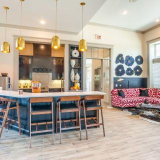 A modern open floor plan combines a stylish kitchen and a comfortable living area, featuring decorative elements and cozy seating.
