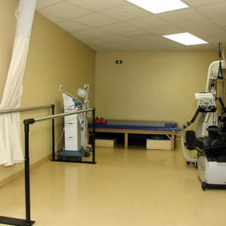 A rehabilitation clinic room equipped with exercise devices and therapy tools.