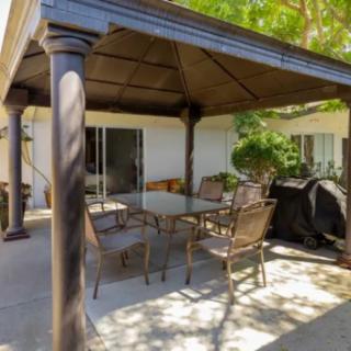 A cozy backyard patio with a gazebo, featuring a table, chairs, and a barbecue grill.