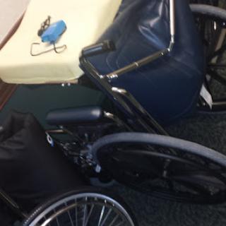 A wheelchair and various items scattered on the floor, including a mattress.