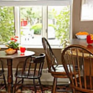 A cozy kitchen dining area with wooden tables and chairs near a bright window.