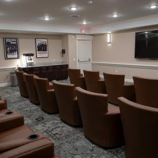 A cozy home theater room with multiple rows of comfortable seating and a large screen.