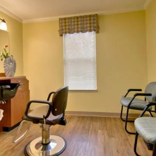 A cozy salon interior with styling and waiting chairs, yellow walls, and a window.