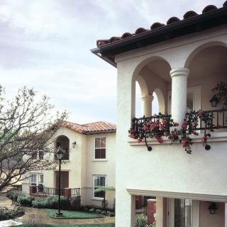 Mediterranean-style houses with balconies and columns on a calm residential street.
