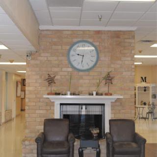 A cozy waiting area featuring a clock and a fireplace, with comfortable seating.