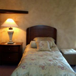 A cozy bedroom with a single bed, lamp, and nightstand.