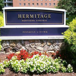 Sign for Hermitage Northern Virginia surrounded by landscaped flowers.
