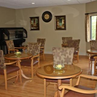 A cozy seating area with wooden tables and patterned chairs, featuring wall artwork and a clock.