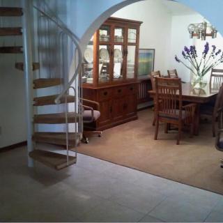 A cozy dining room featuring a wooden table and chairs, with a spiral staircase leading to an upper level.
