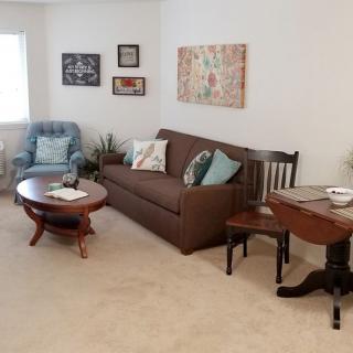 A cozy living room with a sofa, chair, and coffee table, adorned with artwork on the walls.