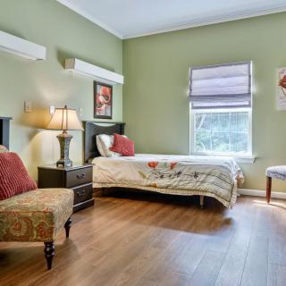 A cozy bedroom with a single bed, soft lighting from a lamp, and green-painted walls.