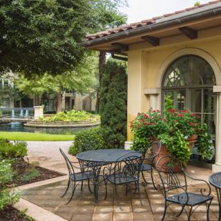 A serene patio with outdoor furniture surrounded by lush greenery and architectural features.