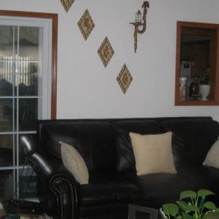 A cozy living room with a dark sofa, neutral cushions, and decorative wall accents.