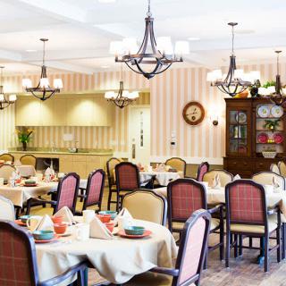 A well-decorated restaurant dining room with tables set for service and elegant chandeliers hanging from the ceiling.