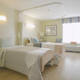 A well-lit hospital room featuring two beds, designed for patient comfort and care.