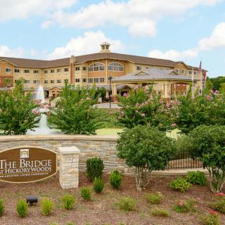 A large, elegant building with a fountain and landscaped garden in front, featuring a sign that reads 'The Bridge'.