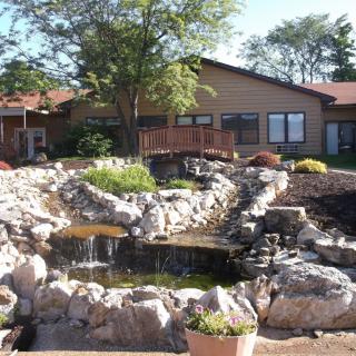 A landscaped garden featuring a rock pond in front of a house.