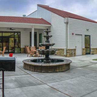 A modern building with a patio featuring a central fountain and outdoor seating.