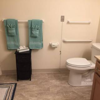 A clean and organized bathroom with teal towels neatly hung beside a toilet.