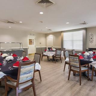 A well-arranged dining area with neatly set tables and chairs, featuring elegant table settings.