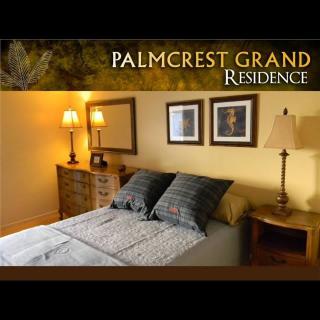 A cozy bedroom interior at Palmcrest Grand Residence, featuring a neatly made bed, bedside lamps, and decorative wall art.