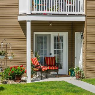 A cozy outdoor patio with striped chairs and lush greenery.