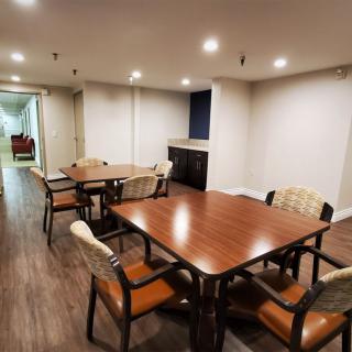 A cozy dining area with wooden tables and chairs, featuring a well-lit interior and wood flooring.