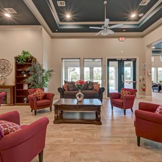 A spacious and elegantly furnished living room with red armchairs, a dark sofa, and stylish decor.